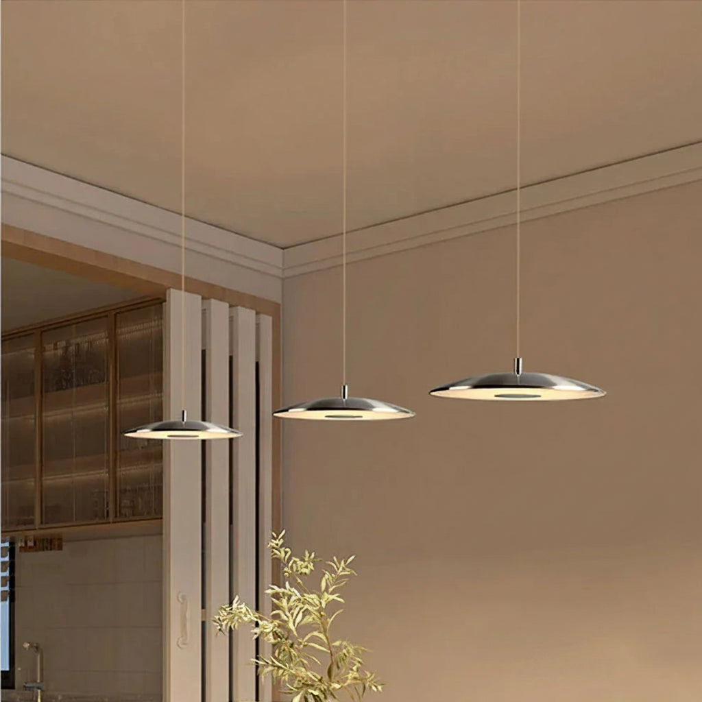 Three modern pendant lights hanging from the ceiling in a room with a neutral color scheme.