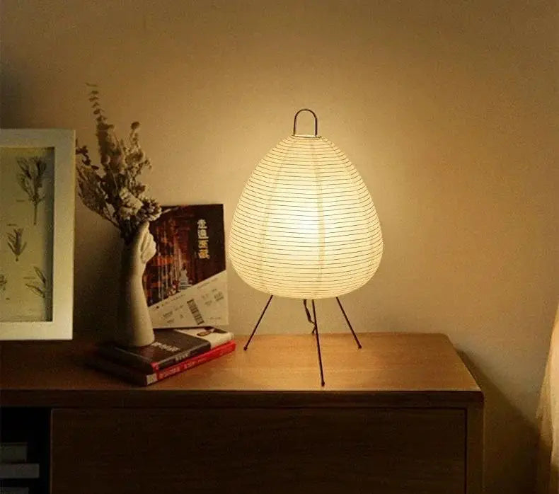 Small egg-shaped rice paper lamp on a slim metal tripod base, 47cm tall and 28cm wide, shown with warm.