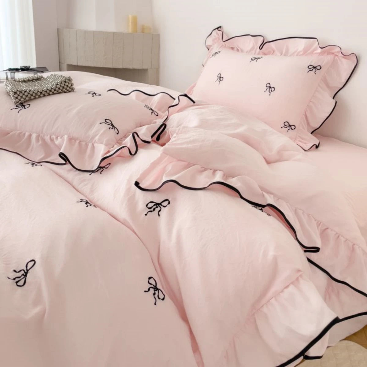 Wide shot of the Soft Blush duvet set on a bed, showcasing the repeating bow pattern and romantic ruffles in a bright, airy room.