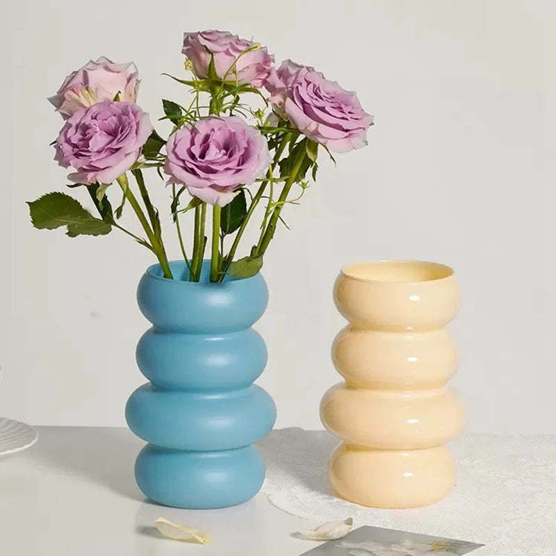 Two vases, blue and yellow, with pink flowers on a light background