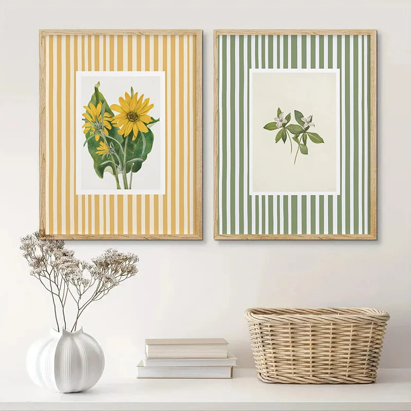 Two framed prints of sunflowers and plants on a wall with decorative items below.