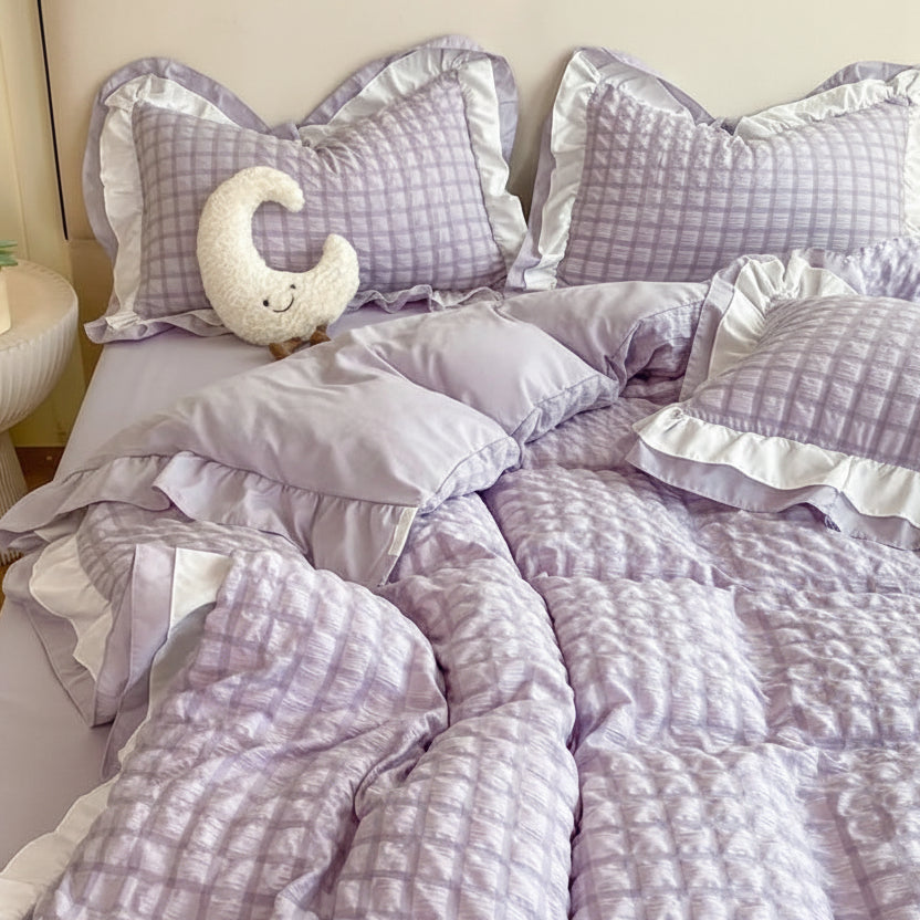 Bed with purple checkered bedding and decorative pillows in a bedroom setting.