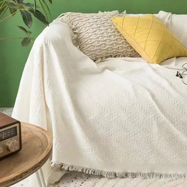 Cream coral fleece sofa cover with fringe trim styled in a bright living room