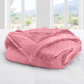 Pink blanket on a bed with a window view of greenery