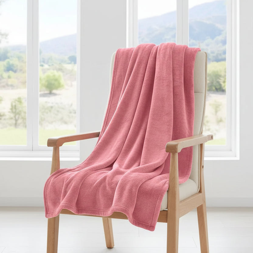Pink blanket draped over a wooden chair with a window view of greenery in the background