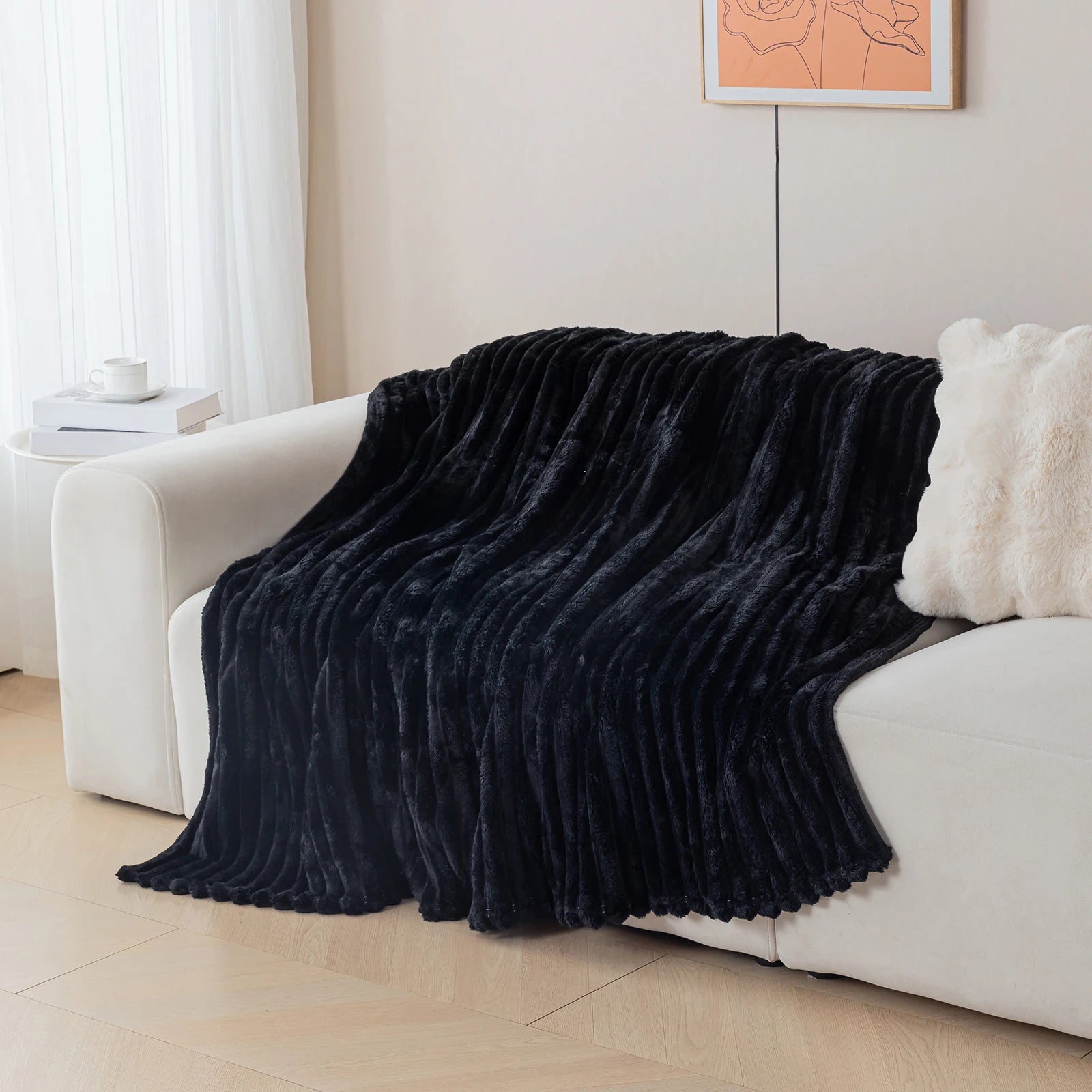 Black blanket draped over a white sofa in a living room setting.