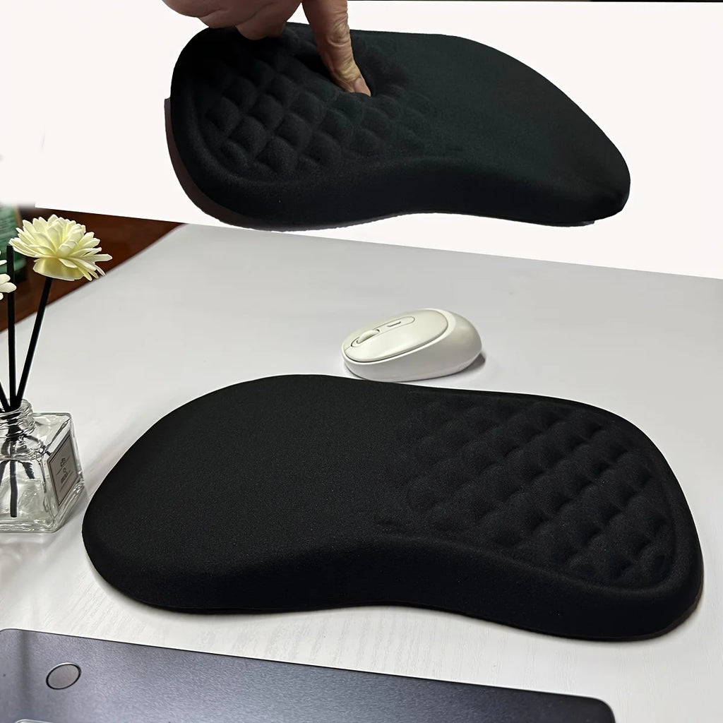 Black ergonomic mouse pad on a desk with a computer mouse and flowers.