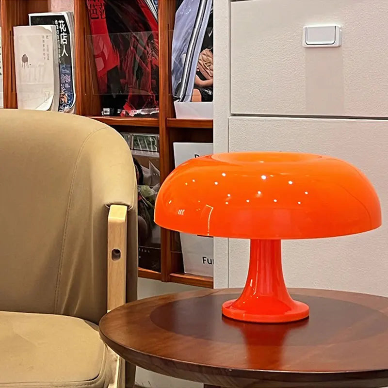 Orange mushroom table lamp on a wooden side table next to a beige chair.