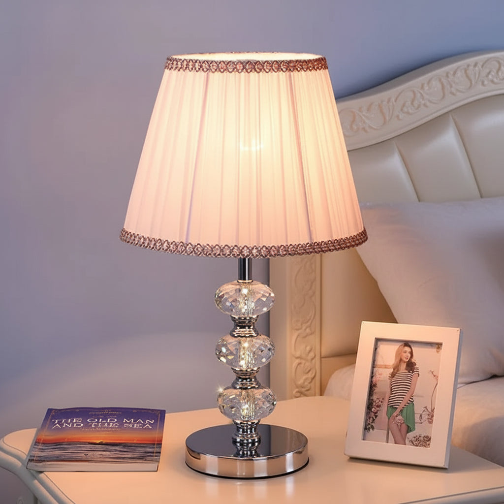 table lamp with a tapered pleated shade and decorative pink-toned trim.