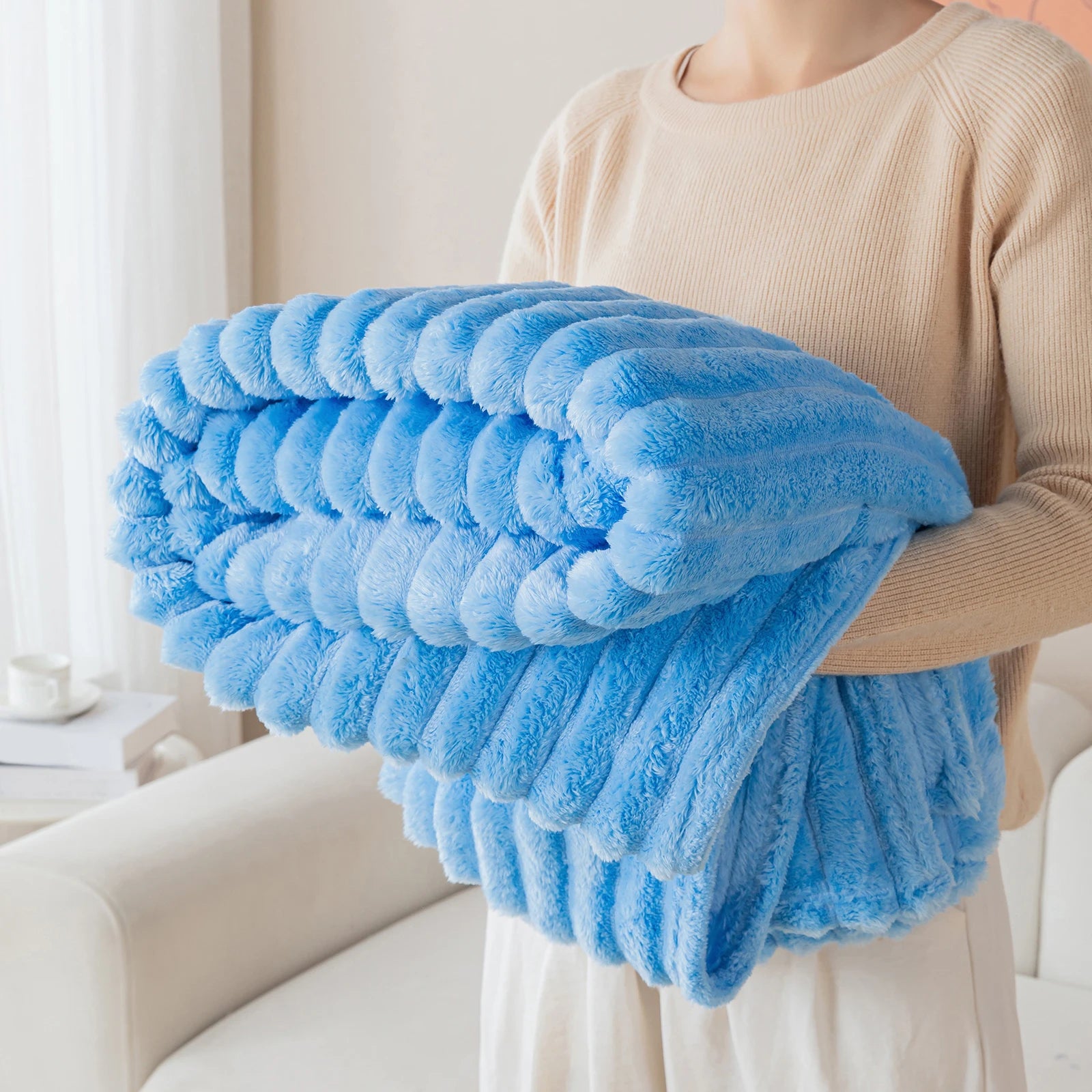 Person holding a blue fluffy blanket in a living room setting