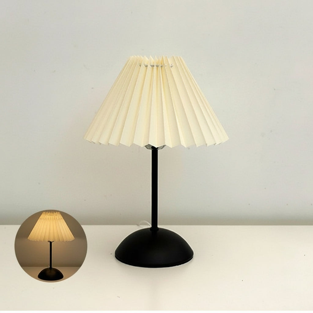 Table lamp with pleated beige shade and black base on a light grey background.