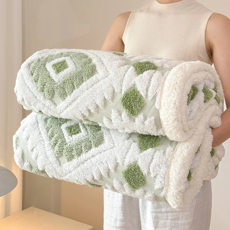 Person holding a sage and white fleece blankets with green floral patterns.