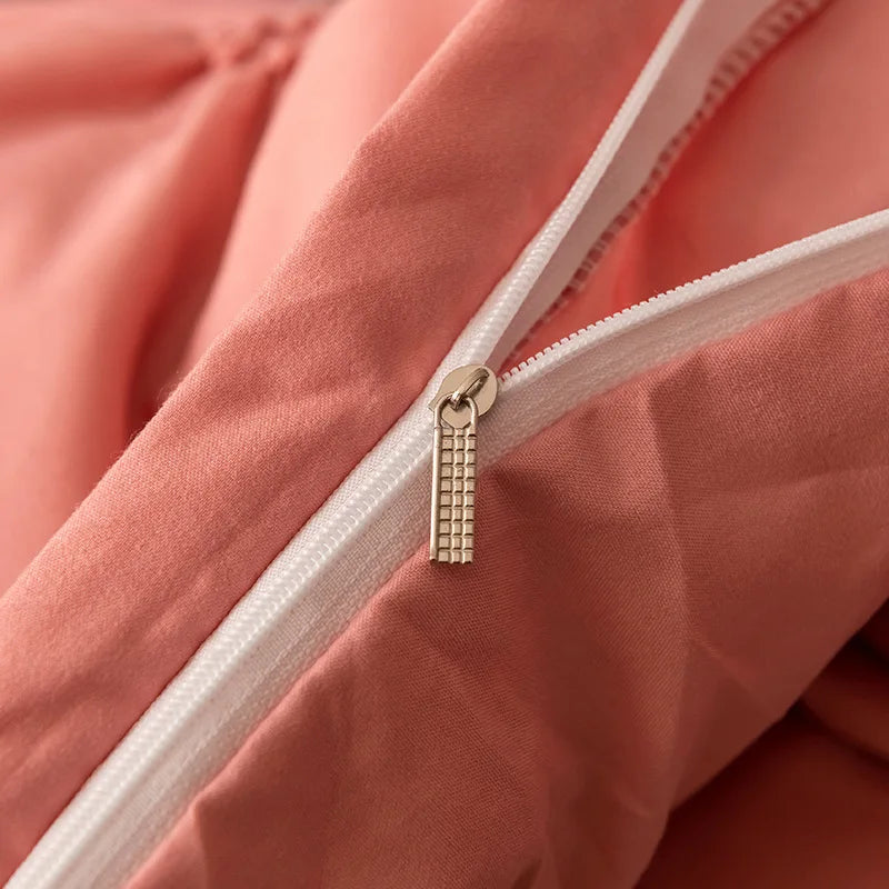 Close-up of a pink duvet with a white zipper and gold zipper pull.