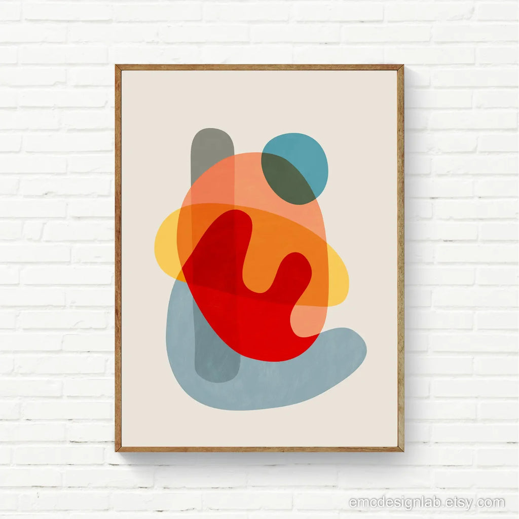 Framed abstract art print with colorful shapes on a white brick wall.