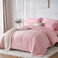 Pink bedding set on a bed in a well-lit room with light-colored walls and decor.