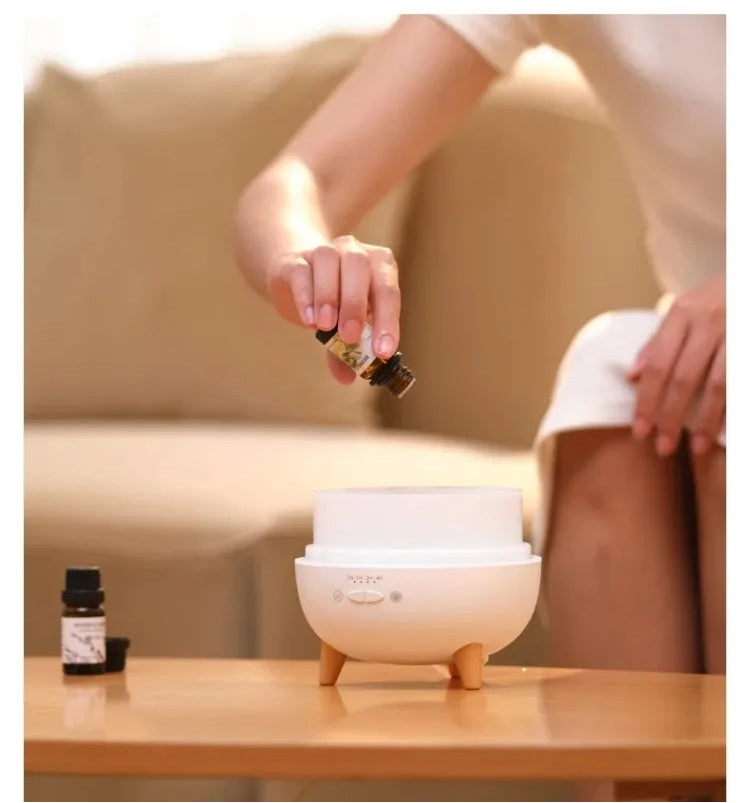 Person adding essential oil to a diffuser on a table