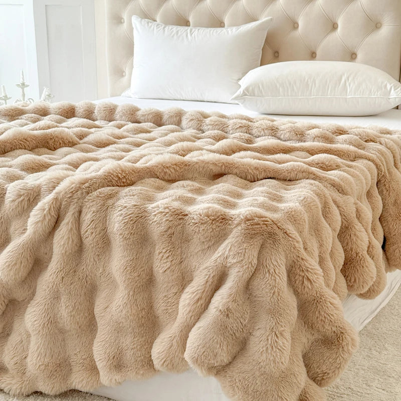 Beige fluffy blanket draped over a bed with white pillows and a tufted headboard.