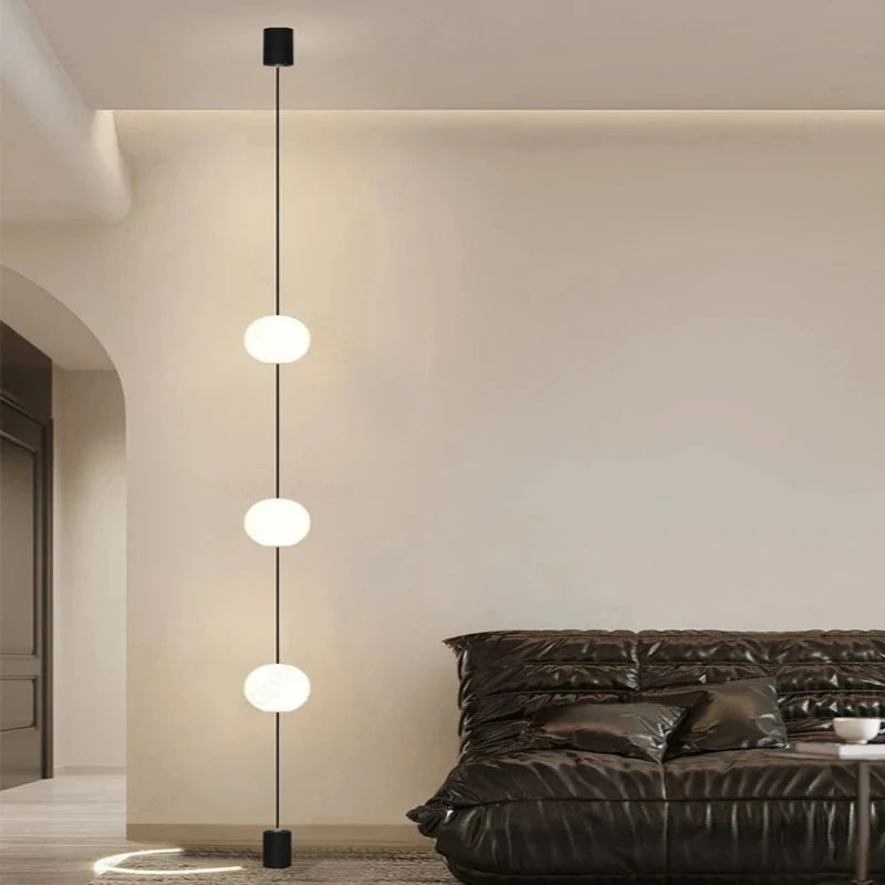 Contemporary lounge space with 3-head floor-to-ceiling LED globe light next to a rounded white armchair