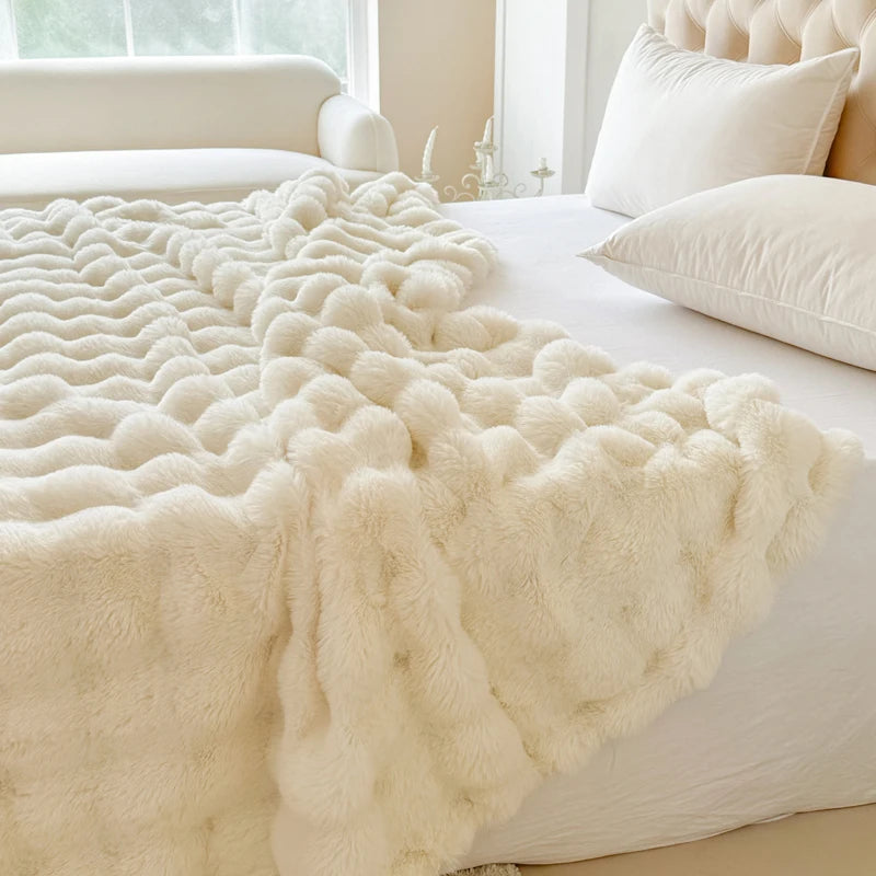 White fur throw blanket on a bed with pillows in a bright bedroom.
