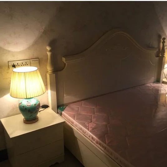 Bedroom scene with a bed and nightstand featuring a lamp.