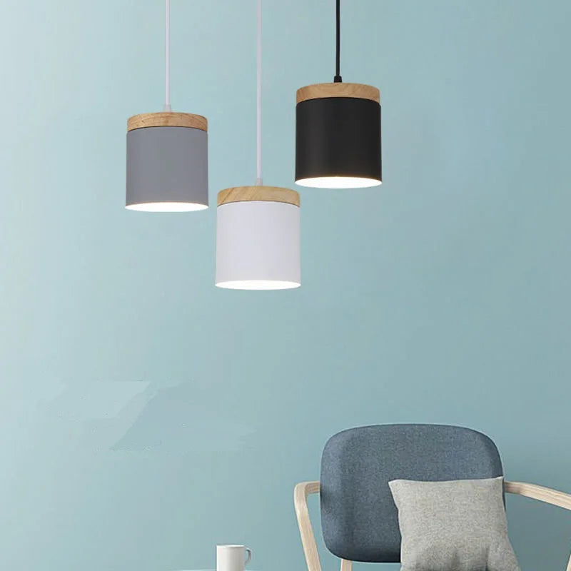 Three pendant lights with wooden accents hanging against a light blue wall.
