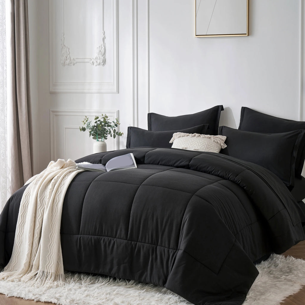 Black comforter set on a bed in a bedroom with white walls and decor.