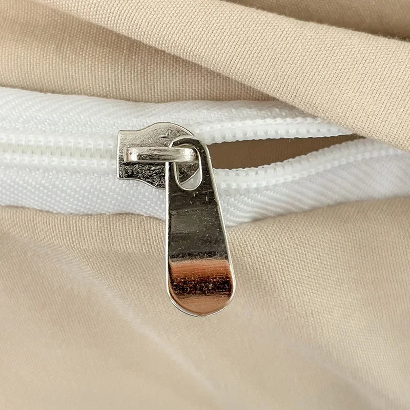 Close-up of a metal zipper pull on beige fabric