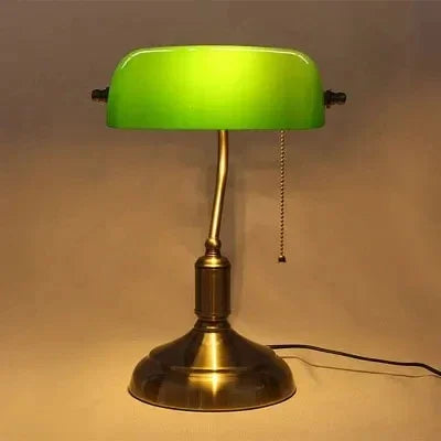 Green glass banker-style desktop lamp with antique brass metal base and pull-chain detail