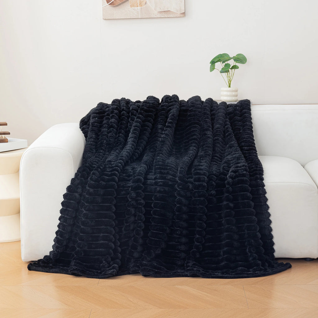 Black textured blanket draped over a white sofa in a living room setting.