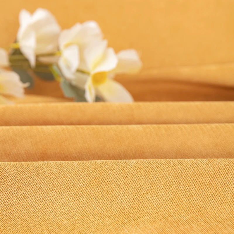 Close-up of yellow fabric with a blurred floral arrangement in the background