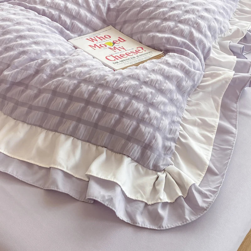 Lavender textured pillowcases with white ruffle trim on the bed