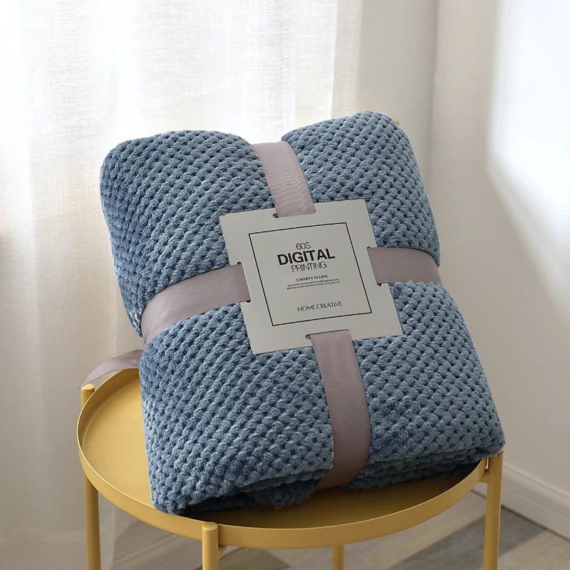 Blue textured blanket with a label on a yellow chair against a white curtain background