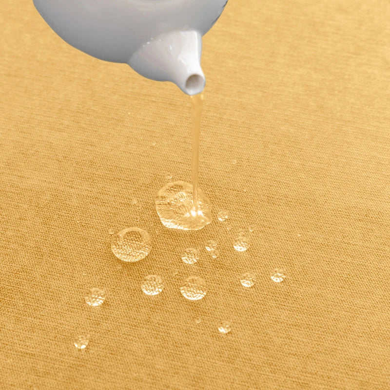 White bottle pouring a clear liquid onto a yellow fabric surface.