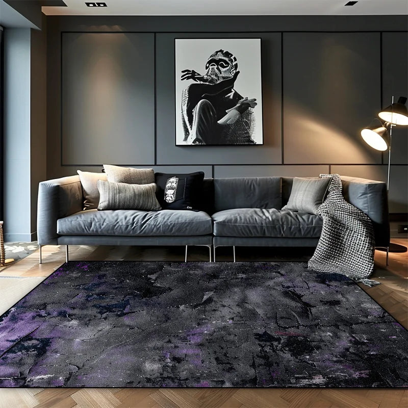 Dark charcoal abstract area rug with deep purple ink wash tones in a moody modern living room with grey sofa
