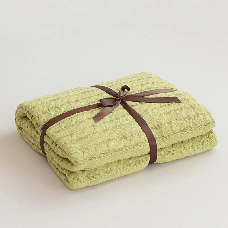 Folded green blanket tied with a brown ribbon on a light background
