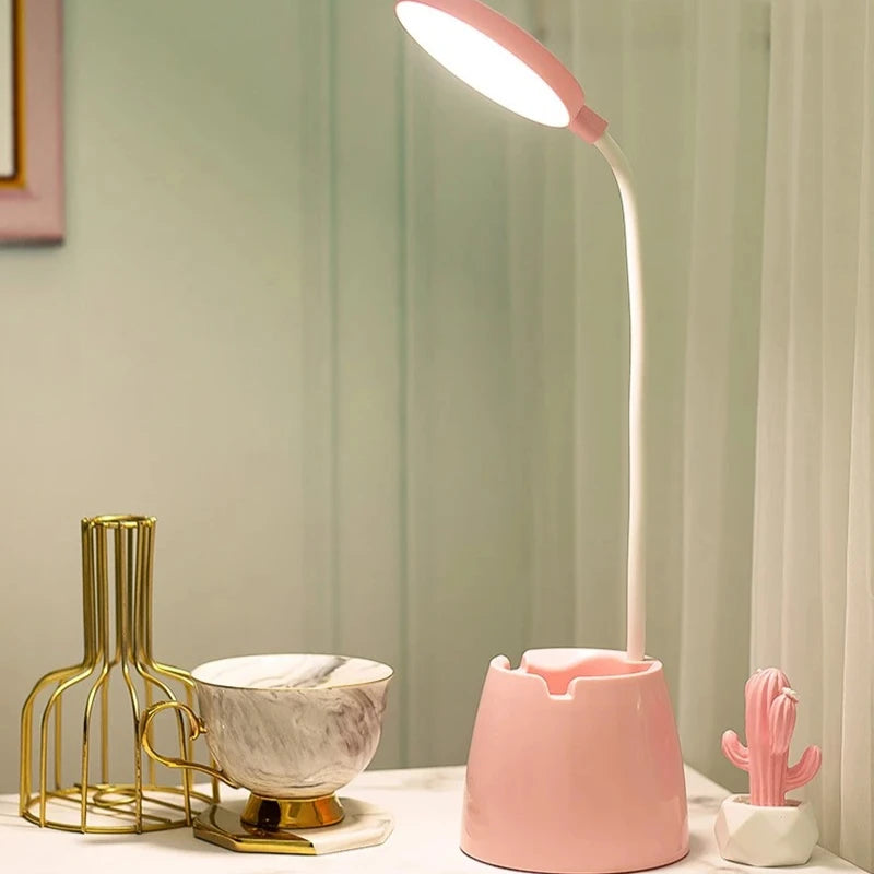 Pink desk lamp on a surface with decorative items in the background