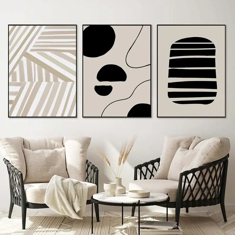 Abstract art prints on a wall above a living room setup with a sofa and chairs.