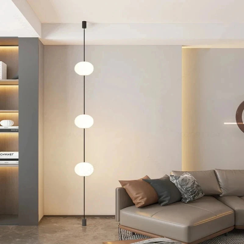 Contemporary lounge space with 3-head floor-to-ceiling LED globe light next to a rounded white armchair
