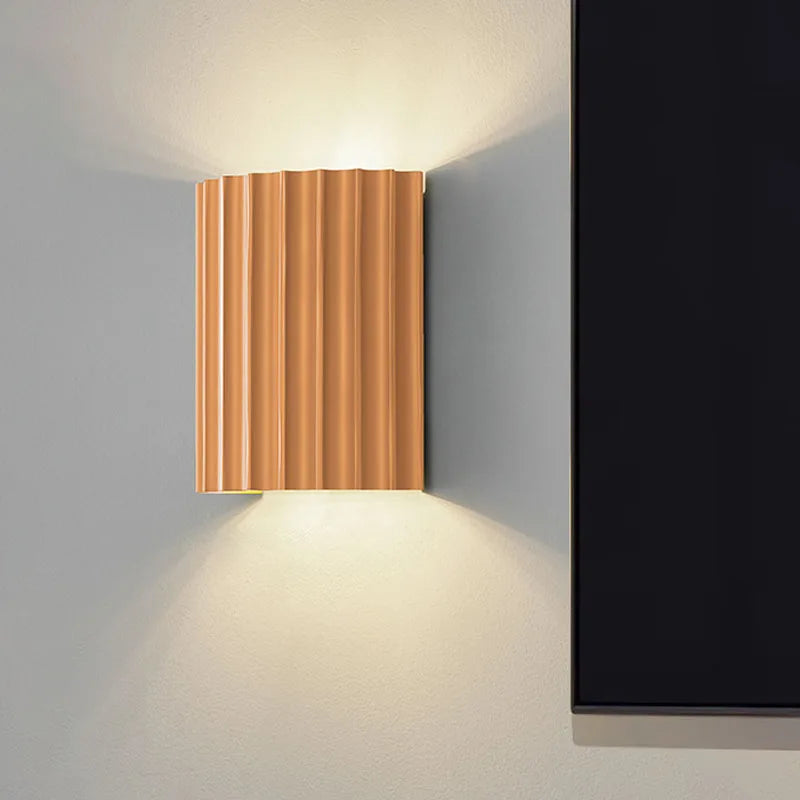 Orange ribbed resin wall lamp with warm-toned fluted shade.