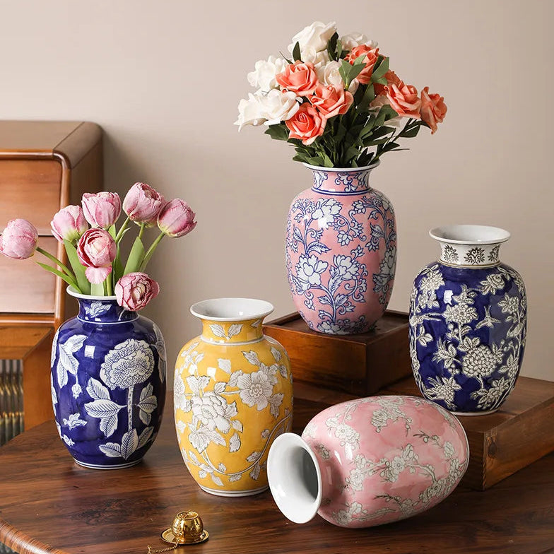 Set of decorative vases with floral patterns on a wooden table against a beige wall.