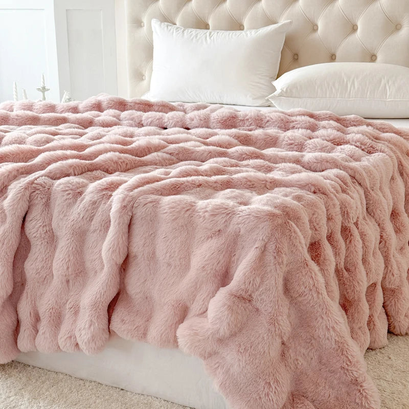 Pink fluffy blanket on a bed with a tufted headboard