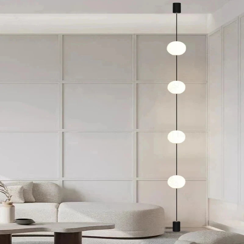 Modern neutral living room featuring a 4-head vertical globe floor light beside a curved sofa