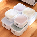 Set of white food storage containers with lids on a wooden floor