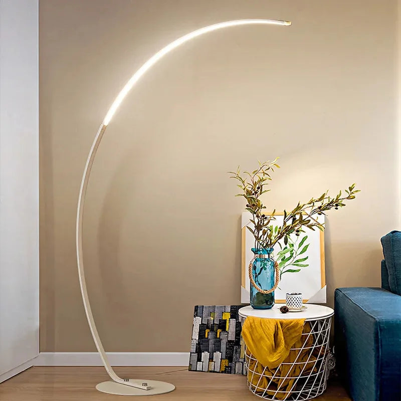 Modern floor lamp in a living room setting with a vase and plant on a table.