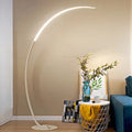 Modern floor lamp in a living room setting with a vase and plant on a table.