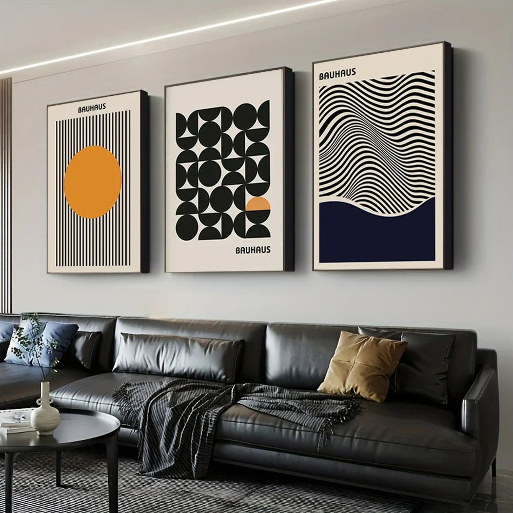 Modern living room with a black leather sofa and three abstract art prints on the wall.