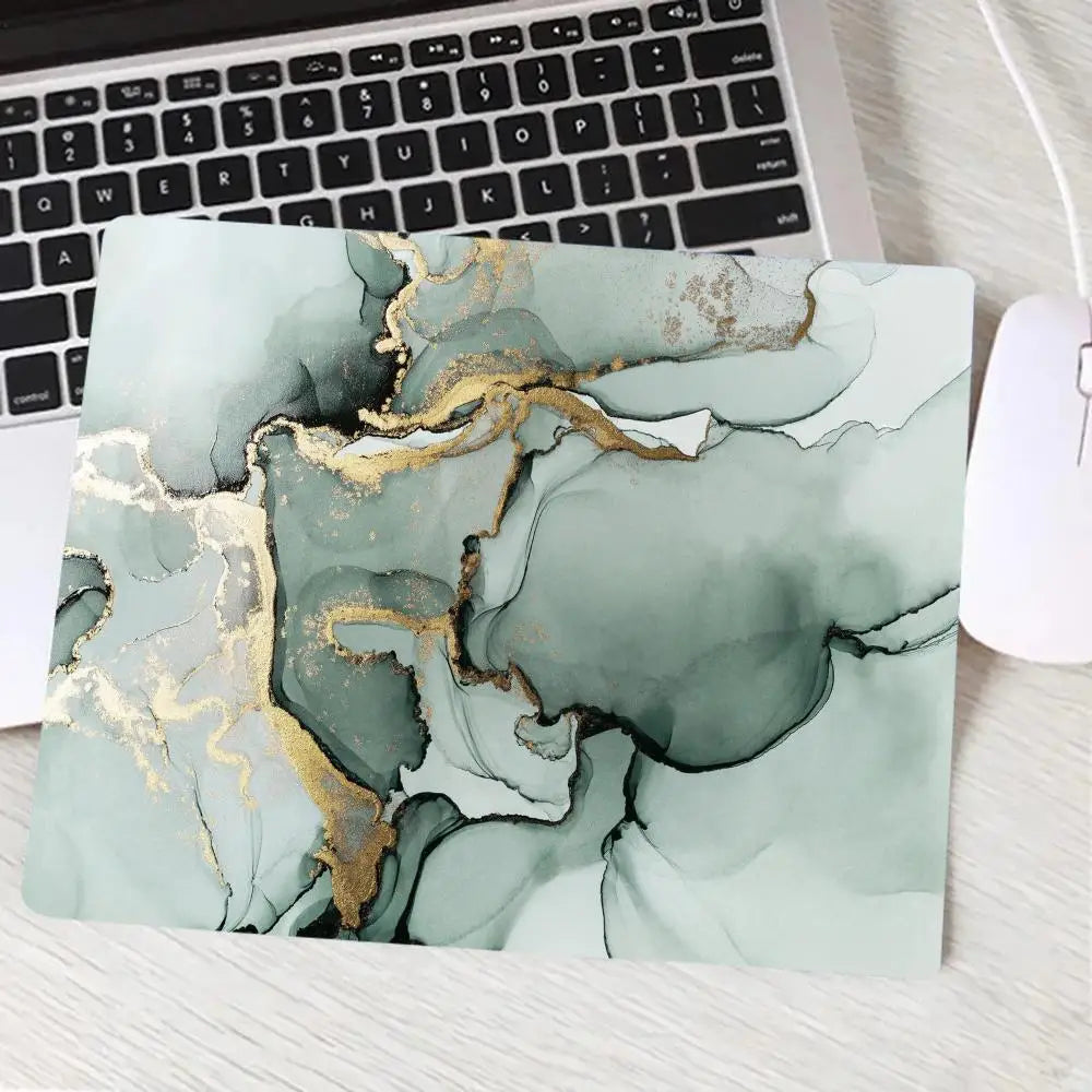 Laptop with a marble-patterned cover featuring gold accents on a desk.
