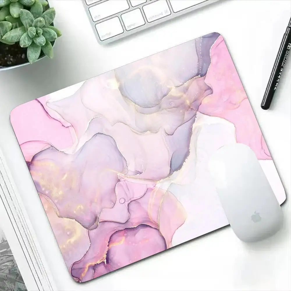 Mouse pad with pink and purple abstract design on a desk with a keyboard and mouse.
