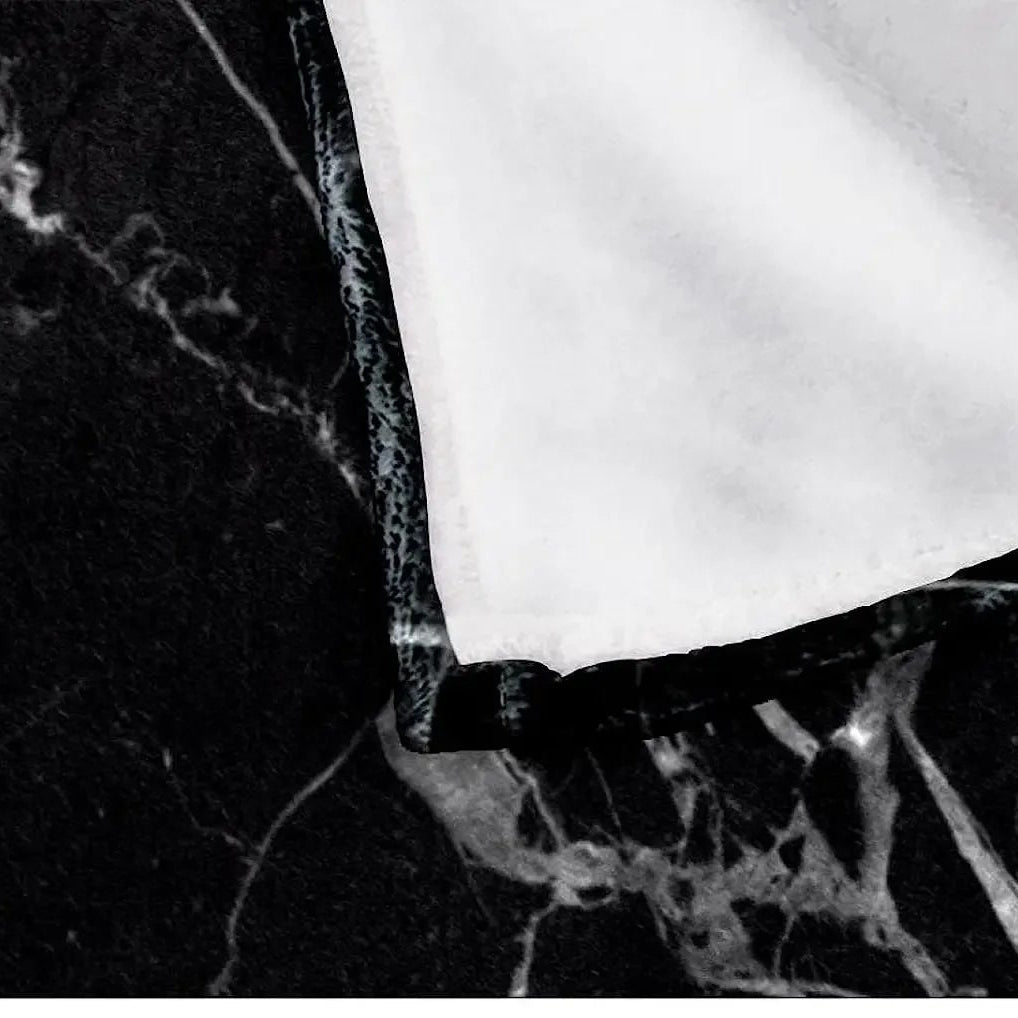 Close-up of the black marble-style blanket showing the white reverse side and single-sided printing