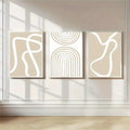 Three abstract line art canvases displayed above a beige sofa in a modern living room.
